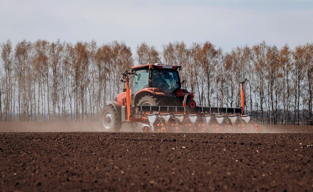 spring-sowing-season-farmer-with-a-tractor-sows-corn-seeds-on-his-field-planting-corn-with-trailed-planter-farming-seeding-the-concept-of-agriculture-and-agricultural-machinery_194143-5816